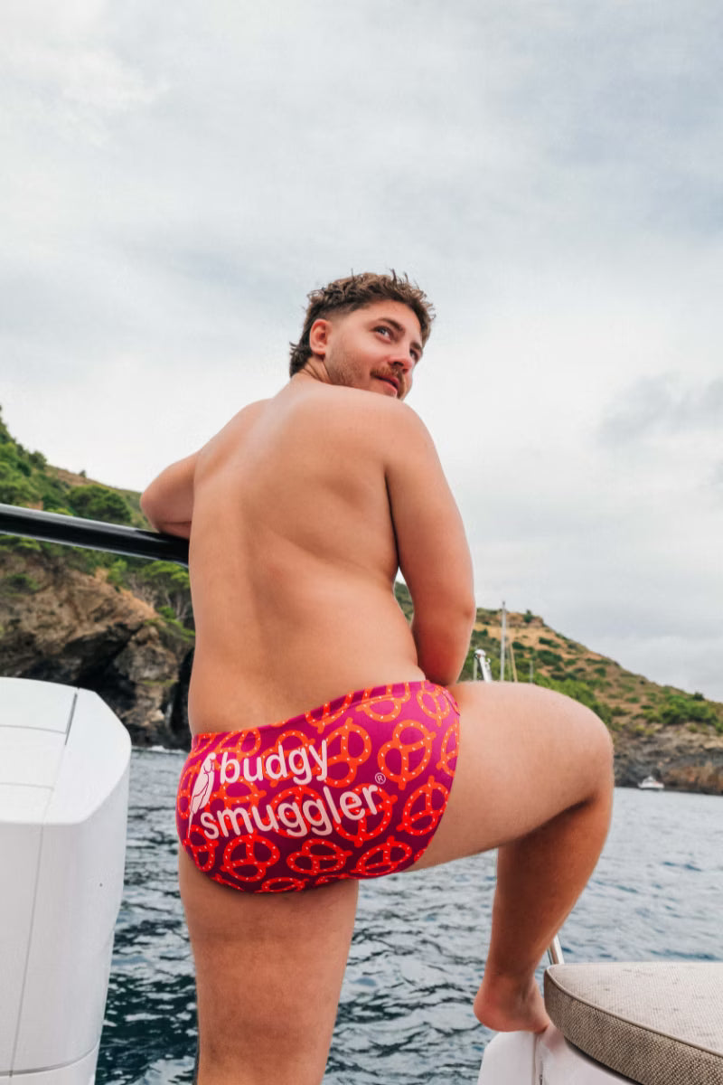 Red mens swim brief with a pretzel pattern  by the water 